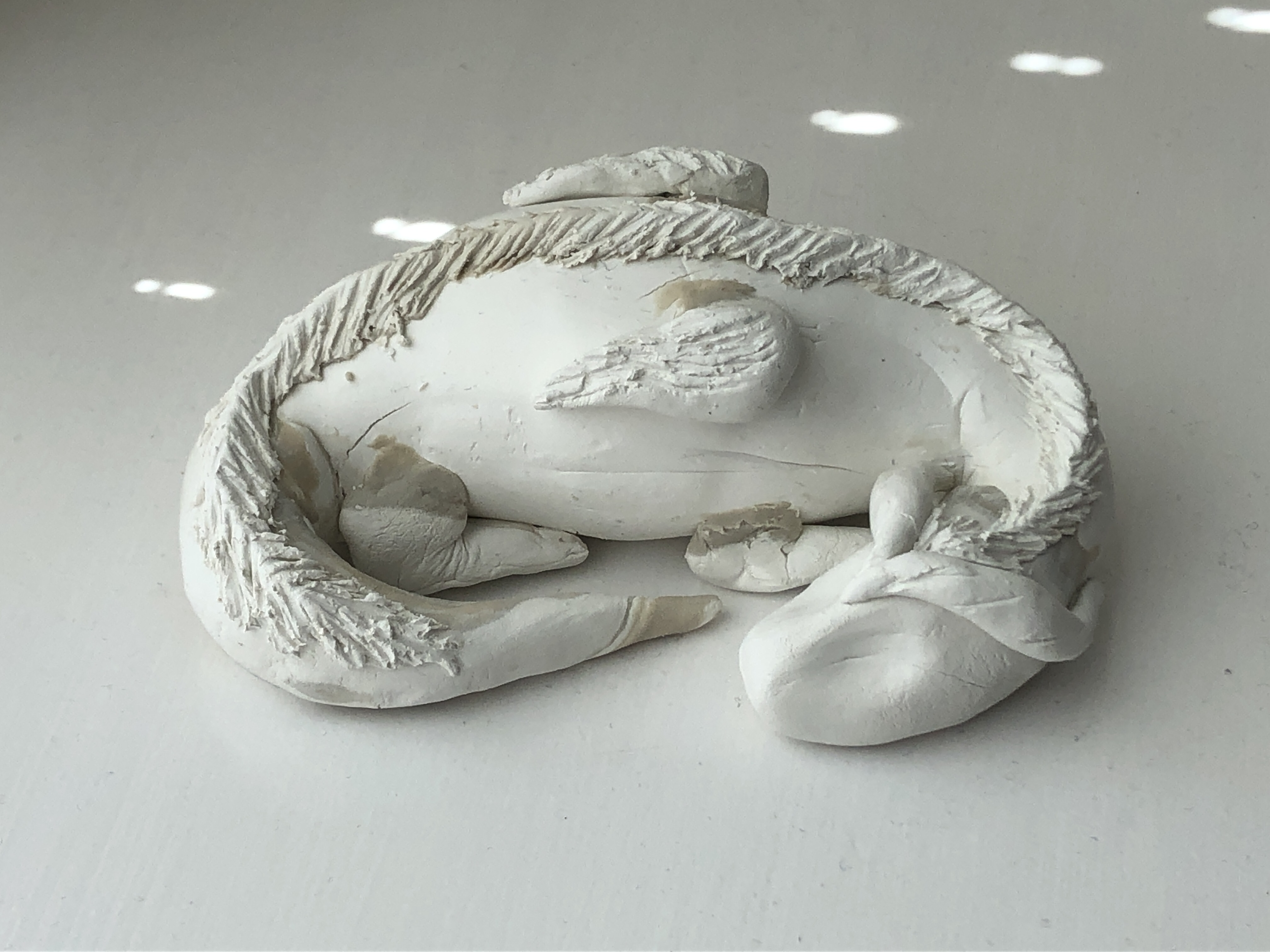 a clay statue of a round sleeping dragon
